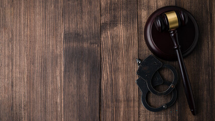 Obraz na płótnie Canvas Gavel with stand and handcuffs on a wooden background top view
