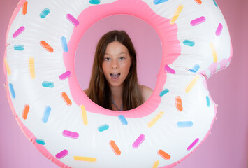 Fototapeta premium Smiling girl with a big float on pink background