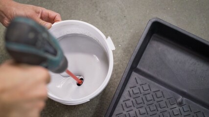 The white paint is mixed in a bucket with a drill. Drill paddle mixer on a bucket with white paint, DIY tools and accessory, banner © Ruslan