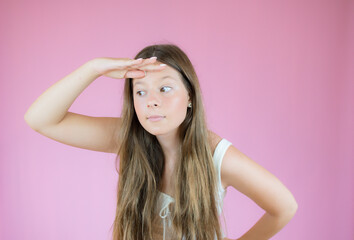 Girl with long hair watching something on pink background