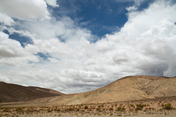 Fototapeta premium Desert landscape. Majestic view of the arid valley and mountains under a dramatic cloudy sky. 