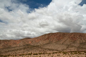 Desert landscape. View of the brown hills and arid valley under a beautiful blue sky with white clouds.