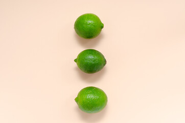 Three fresh juicy bright limes on a gentle pink light background with place for text. citrus vitamin C healthy eating. blank for postcards banner and menu