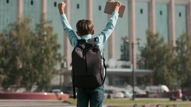 Online education, Back to school, Happy schoolboy, Learn lessons. The schoolboy is happy that he has returned to school, jumps and raises his hands up