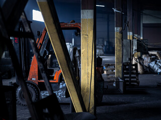 Red forklift parked in modern factory warehouse. Dark light. yellow pillar