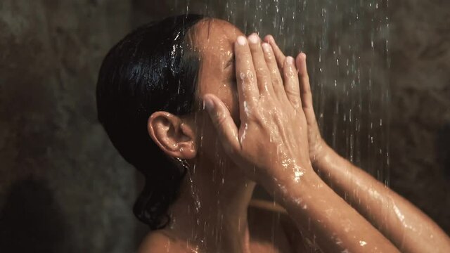 A woman taking shower. Close up view in shower cabin under splashing water