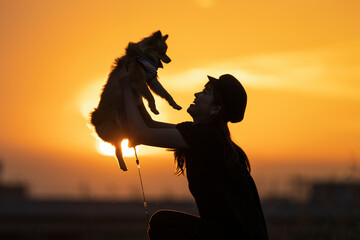 夕日と抱っこされる犬