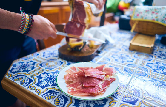 Person cutting ham from the leg of the pork ham with a long knife. Spanish typical food