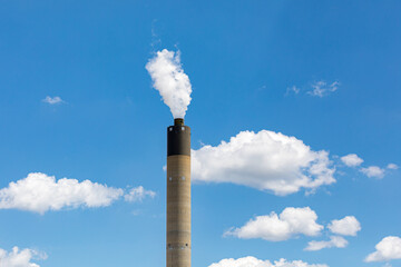 Coal fired power plant smokestack with white smoke rising in the blue sky. Concept of fossil fuel...