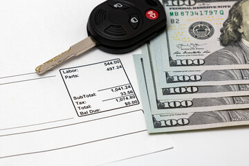 Car key, vehicle repair bill invoice and 100 dollar bills cash. Concept of vehicle manufacturer extended warranty. Automobile maintenance and service costs
