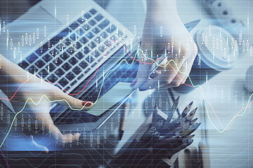 Double exposure of businesswoman hands typing on computer and financial graph hologram drawing. Stock market analysis concept.
