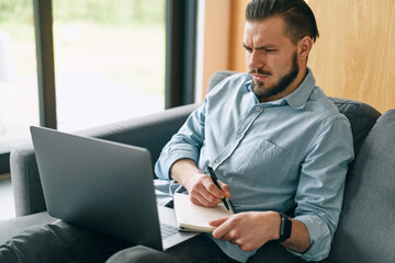 Fototapeta premium Side view of concentrated at work confident young man