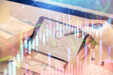 Double exposure of man's hands holding and using a phone and financial chart drawing. Market analysis concept.