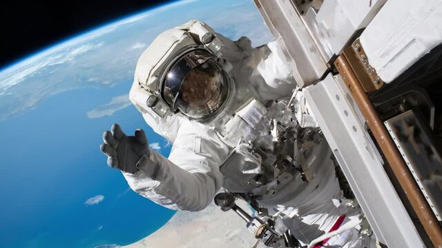 Astronaut waving hand on a spacewalk. Elements of image furnished by NASA.