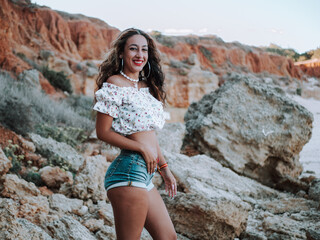 Chica con piercings disfrutando del verano en una playa rocosa con acantilados 