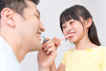 女の子に歯磨き指導をする男性歯科医