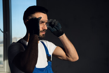 The repairer is in a dark room. He puts on safety glasses