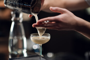Close-up of a glass with a beautiful delicious cocktail standing on the table in a restaurant. The bartender creates an alcoholic drink for women.