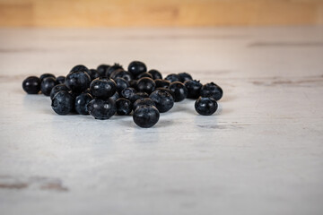 Close up photo of a bunch of sweet fresh organic blueberries piled on a white wooden background 