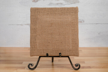 No people blank empty brown burlap rustic square canvas sign sitting on an easel ready to add text or content 