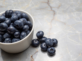 Blueberries in a white pot on a marble table.