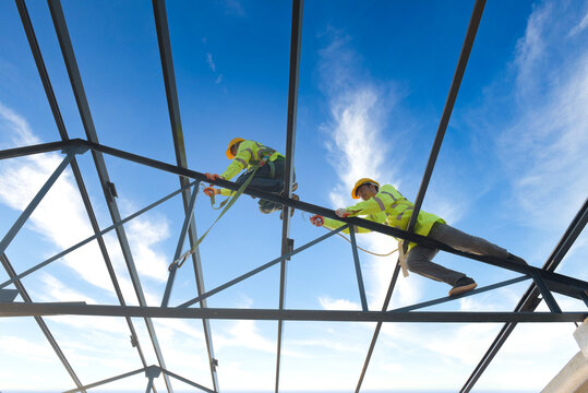 Construction workers wear safety harnesses and safety harnesses working on industrial metal roofs.
