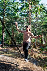 Naklejka na ściany i meble young man doing slackline rodeo in forrest outside sports activities, lifestyle people concept