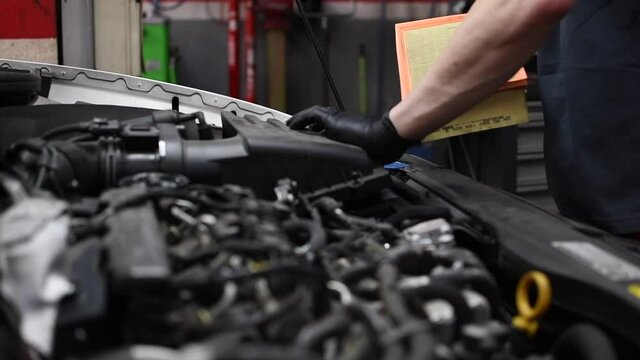 Mechanic removing old air filter from very dirty car inspecting it. Pedestal up camera movement