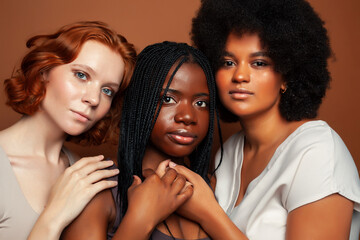 Obraz premium young pretty caucasian, afro, scandinavian woman posing cheerful together on brown background, lifestyle diverse nationality people concept