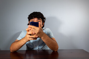 Wavy hair young hispanic man using smart phone and showing various emotions