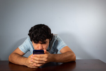 Wavy hair young hispanic man using smart phone and showing various emotions