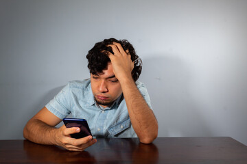 Wavy hair young hispanic man using smart phone and showing various emotions