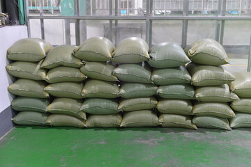 Many rows of plastic white sacks with goods are in big warehouse