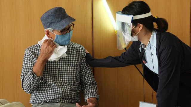 避難所イメージ　災害にあって避難所の体育館に避難してきたシニアの夫婦にインタビューするレポーター