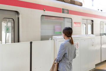 Fototapeta na wymiar マスク姿で電車通勤をする女性