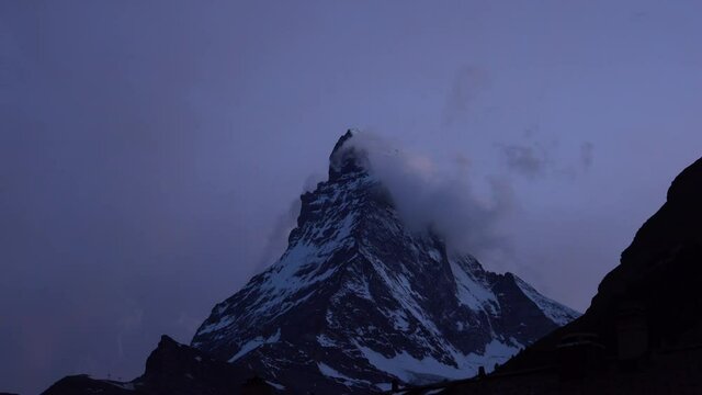 Matterhorn mountain summit Timelapse at dusk with clouds passing in front of the summit and unveiling the peak taken from Zermatt in Swiss Alps Switzerland