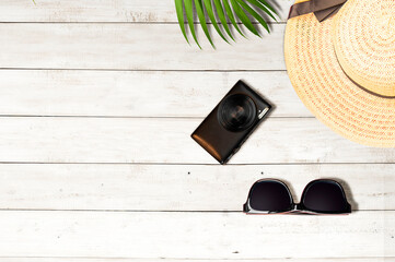 Top view of a hat, camera, and sunglasses with a wooden background