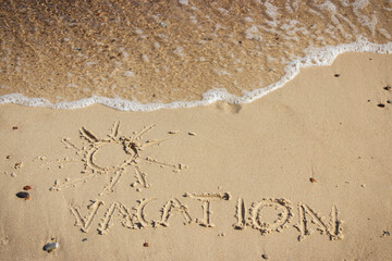 Inscription vacation with shape of sun and incoming sea wave on sand at beach. Summer time