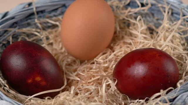 Easter colored eggs lying in the dried grass in a blue basket. Horizontal wiring