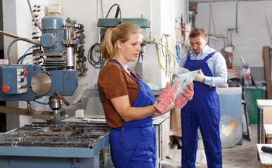 Experienced female worker of glass factory drilling bores in glass on machine.