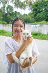Asian teenager holding  white cat in her hands