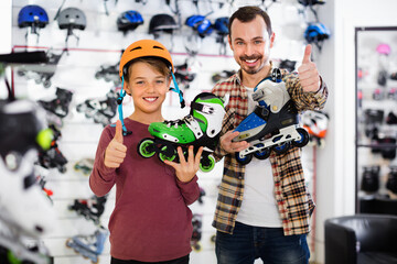 Cheerful positive father and son showing roller-skates they bought in sports store