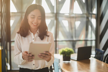 Smiling Asian business woman working on tablet at her desk. Business woman working from home in quarantine.