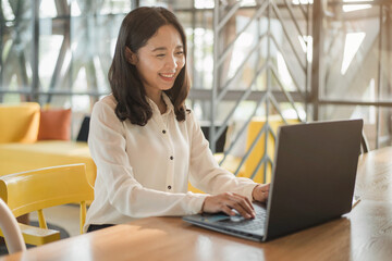 Smiling Asian businesswoman working on a laptop at her desk. Business woman working from home in quarantine.