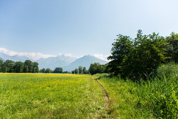 Fototapeta na wymiar Panoramic View of Idyllic Mountain Scenery in the Alps with Fresh Green Meadows.