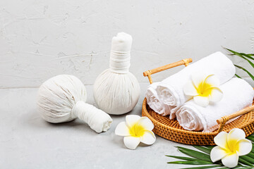 Spa massage Aromatherapy body care background. Spa herbal bags, towel and tropical flowers on gray concrete table. copy space. Beauty and health care concept