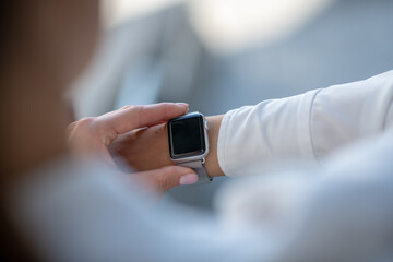 Woman in white shirt looking at the smartwatch