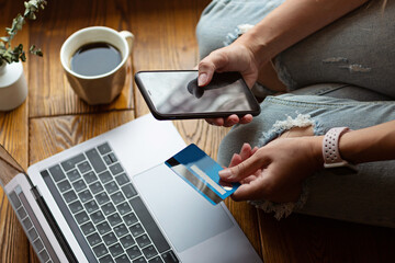 Fototapeta na wymiar Young woman holding credit card and using laptop computer. Online shopping, e-commerce, internet banking, spending money, working from home concept