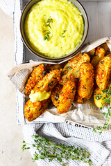 Oven baked crispy potatoes with thyme and cheese sauce in ceramic bowl, light background. Top view.