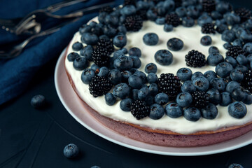 Cottage cheese pie with blackberry and blueberry on dark textured background.